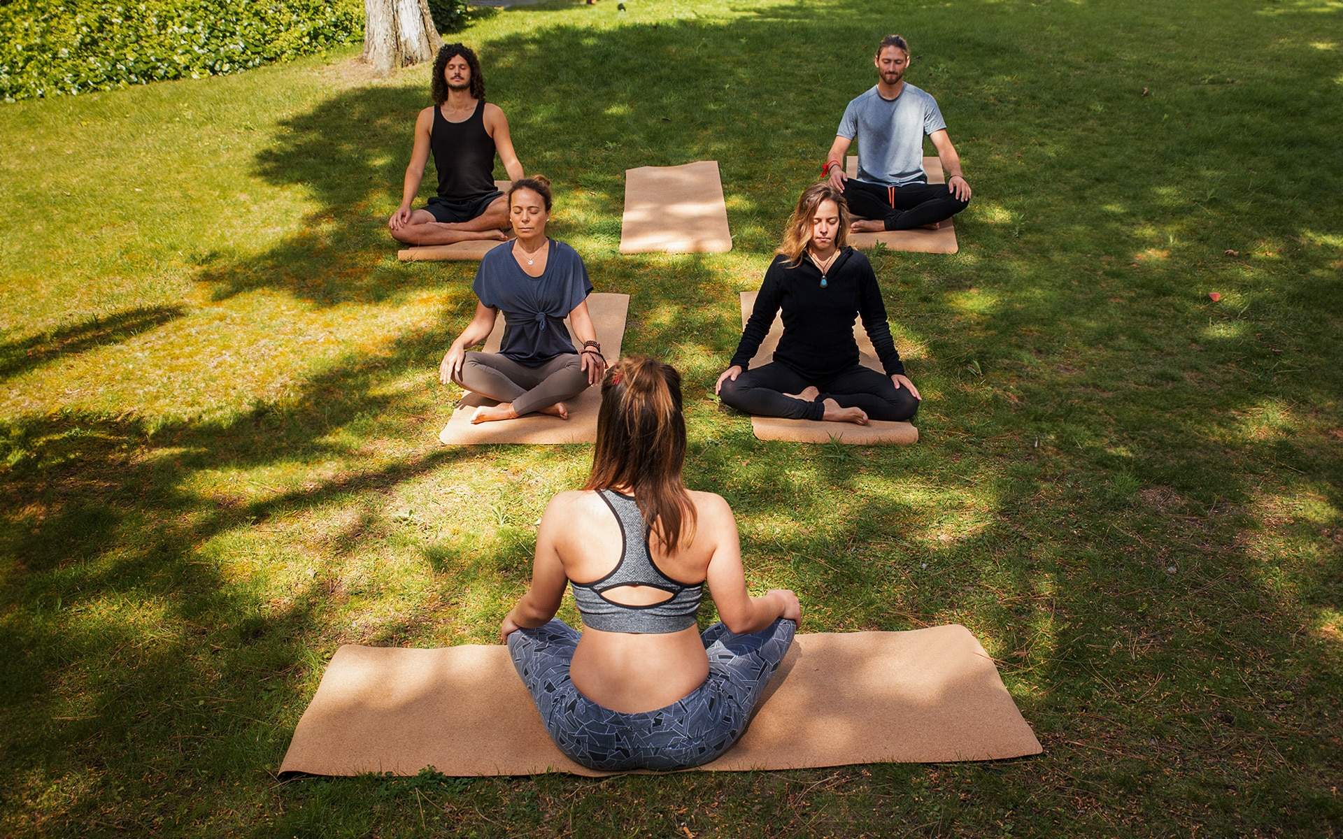 Five people seated on mats outdoors with eyes closed practicing group breathwork showing the difference in energy and support compared to solo breathwork sessions