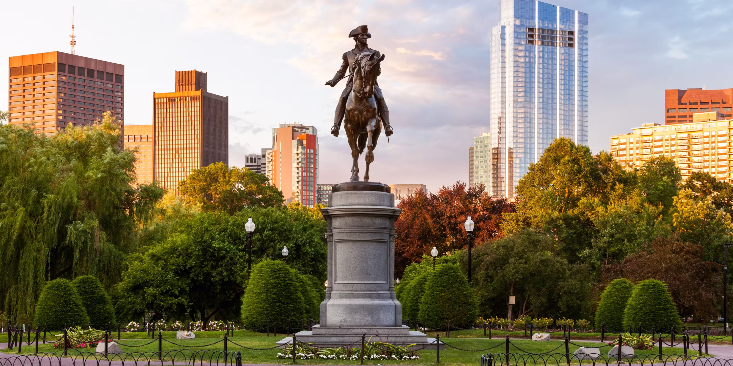 Statue in Boston Public Garden with downtown skyline behind symbolizing Massachusetts’ current legal ban on psilocybin retreats and growing local momentum for reform in 2025